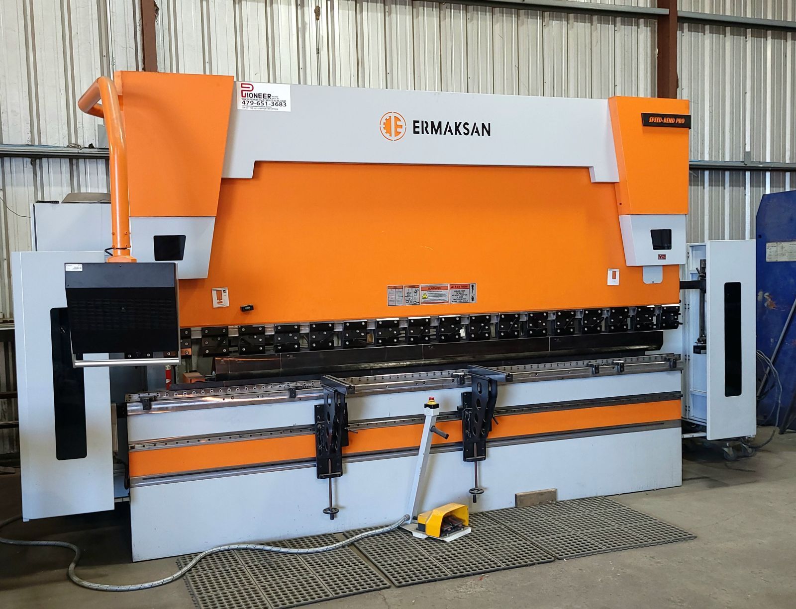 An orange and white machine is sitting on the floor in a warehouse.