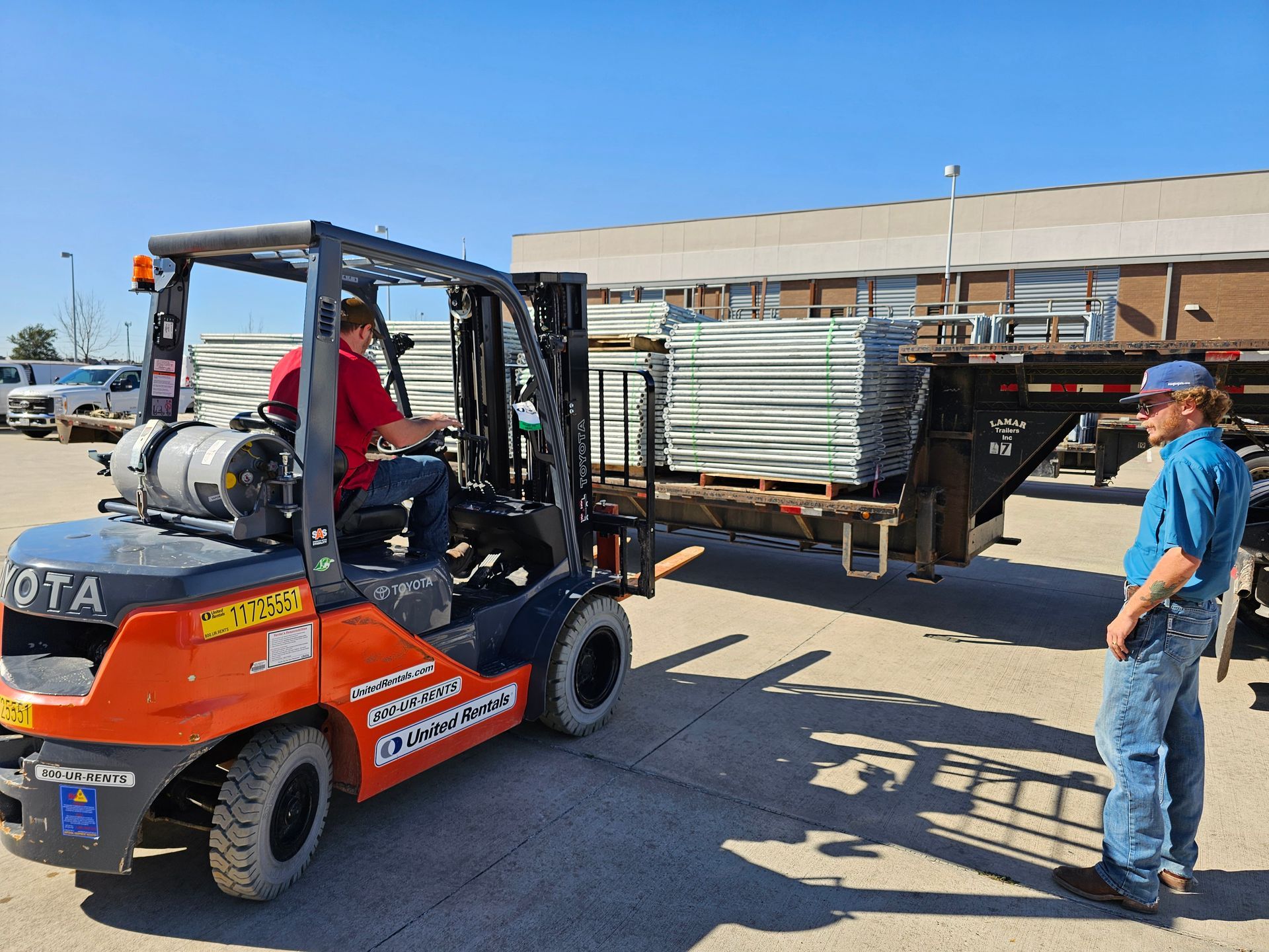 A man is standing next to a forklift in a parking lot.