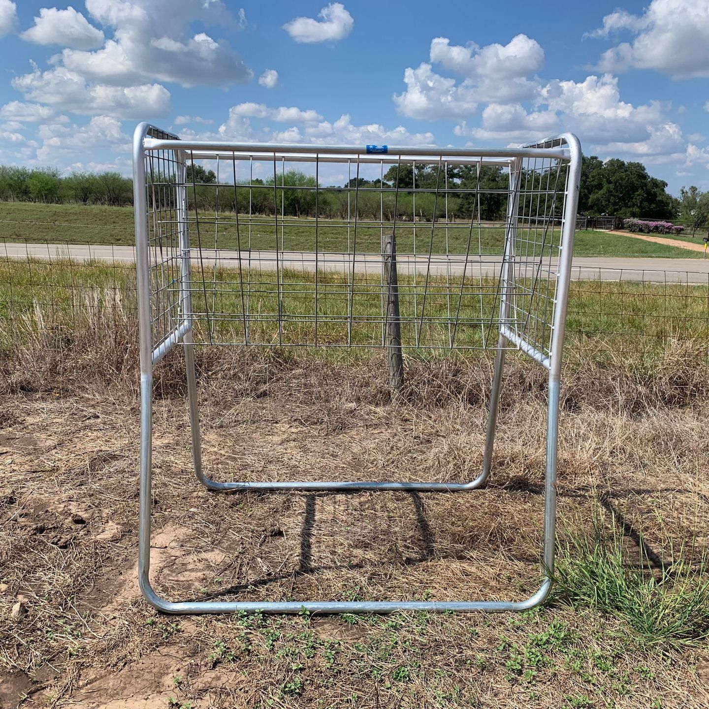 A metal gate is sitting in the middle of a field.