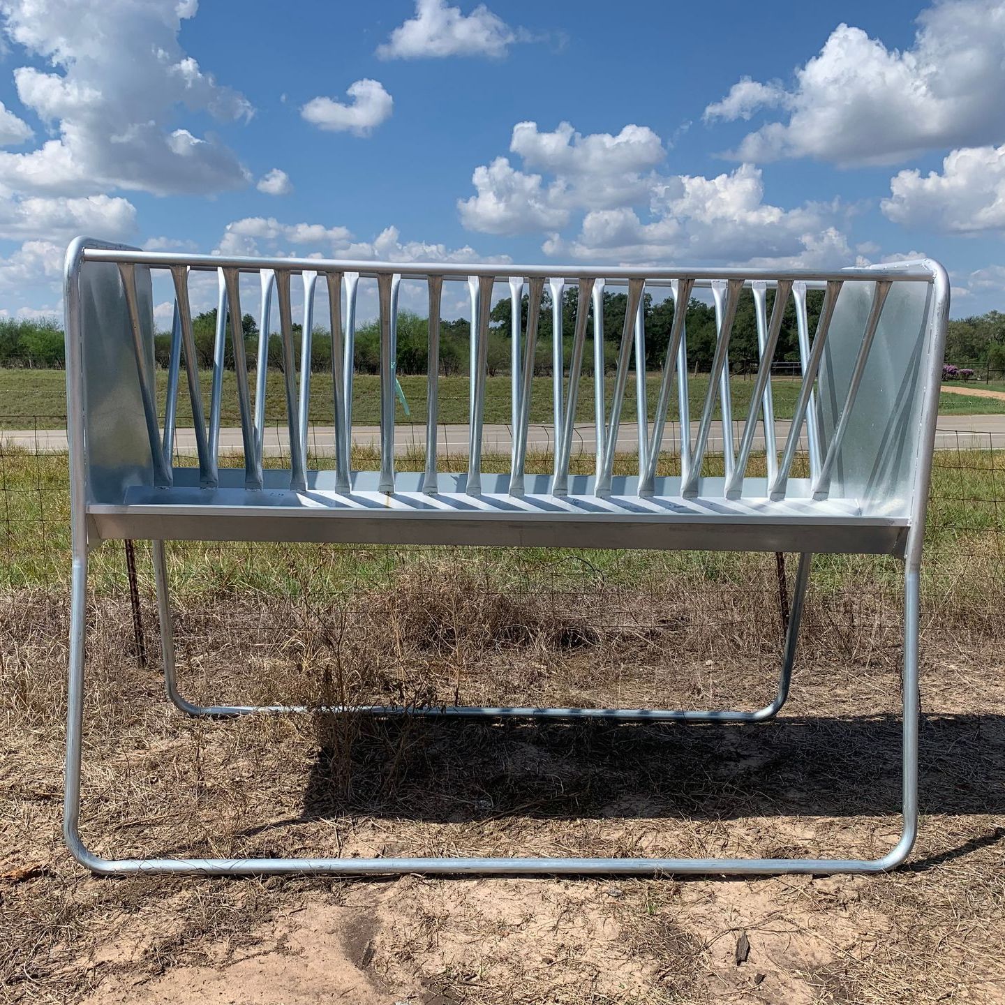 A metal feeder is sitting in the middle of a field.