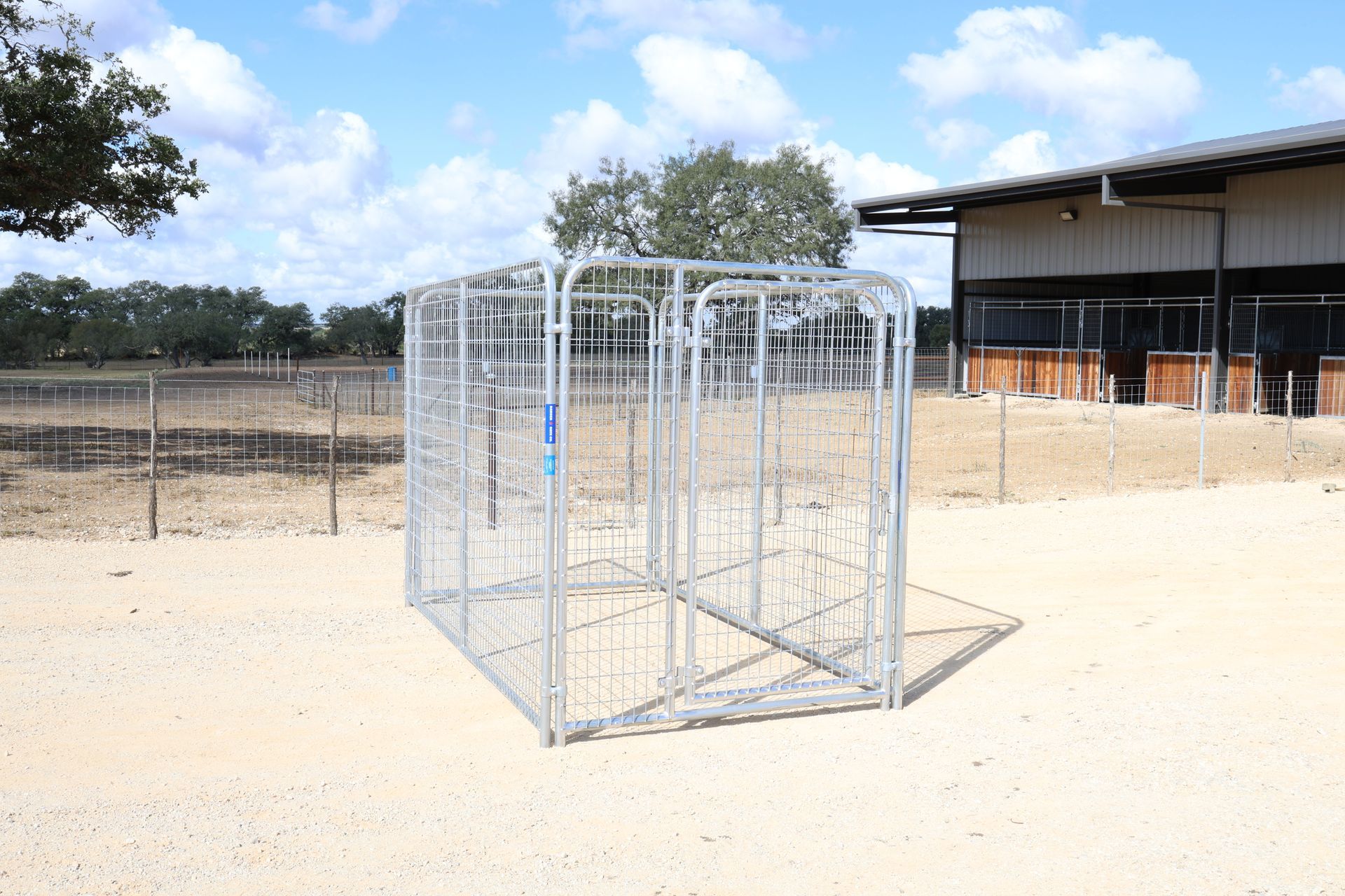 A metal fence is sitting in a dirt field in front of a building.