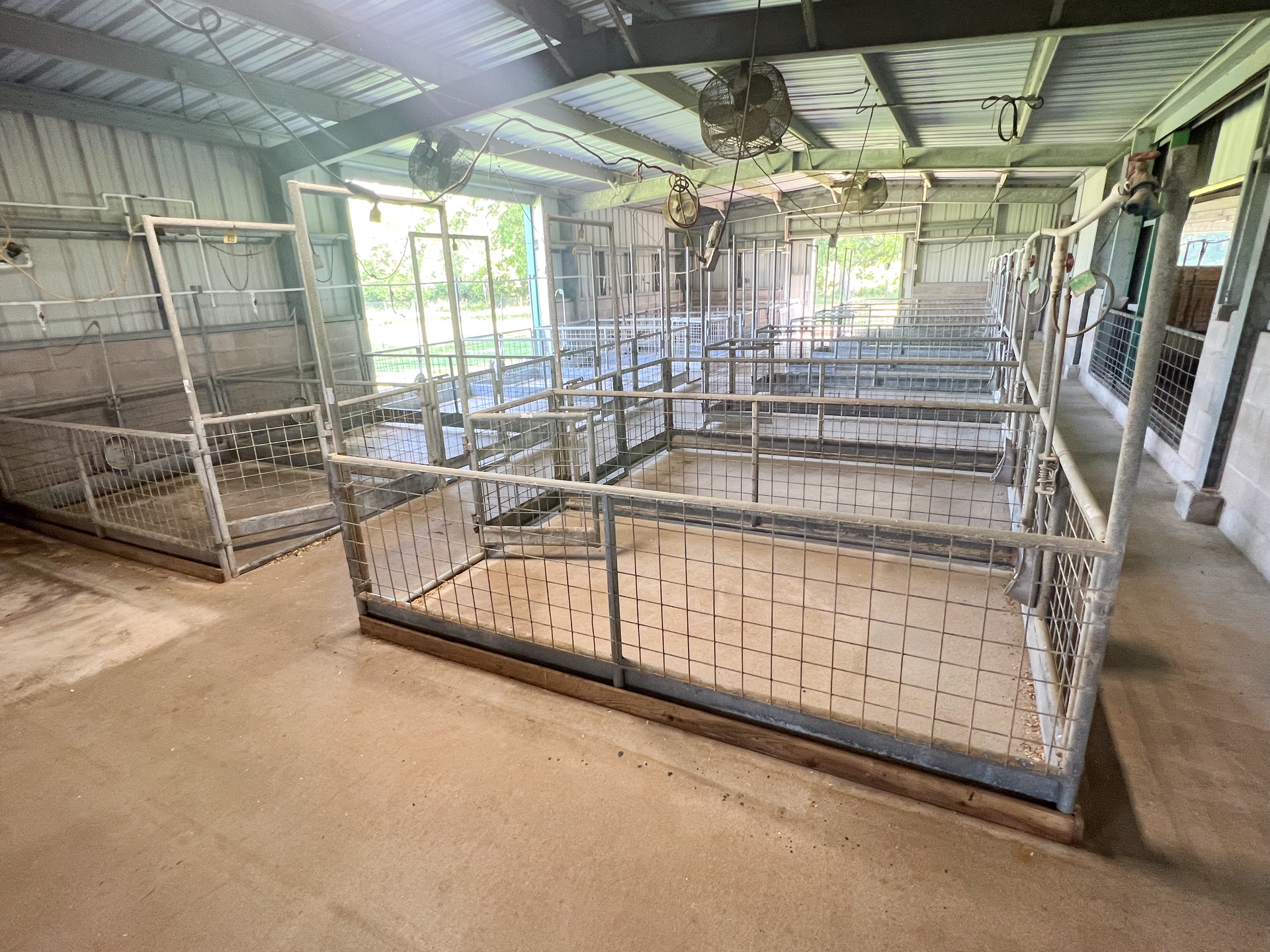 A large empty barn with a lot of cages in it.