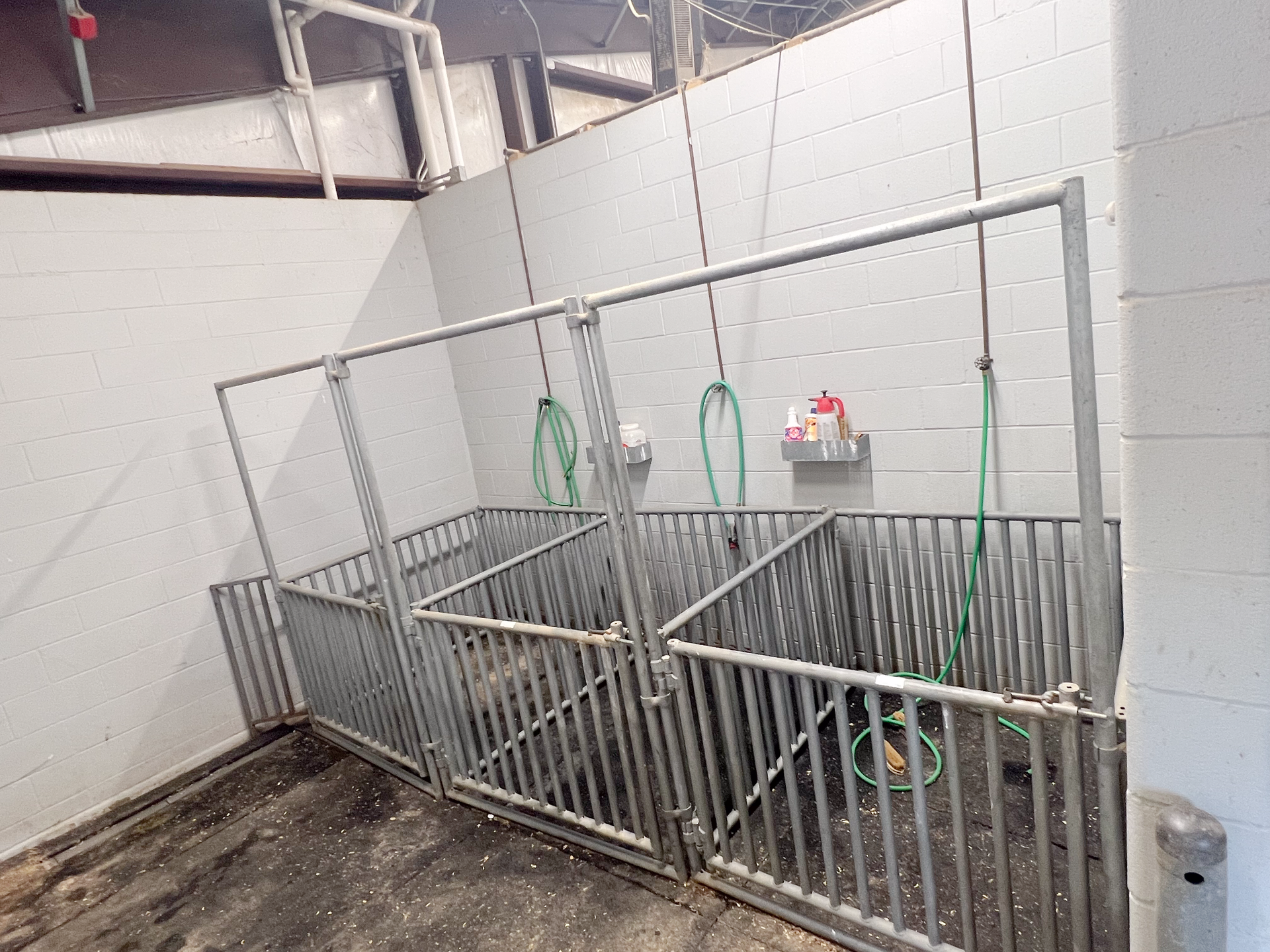 A room with a fence and a hose hanging from the ceiling.