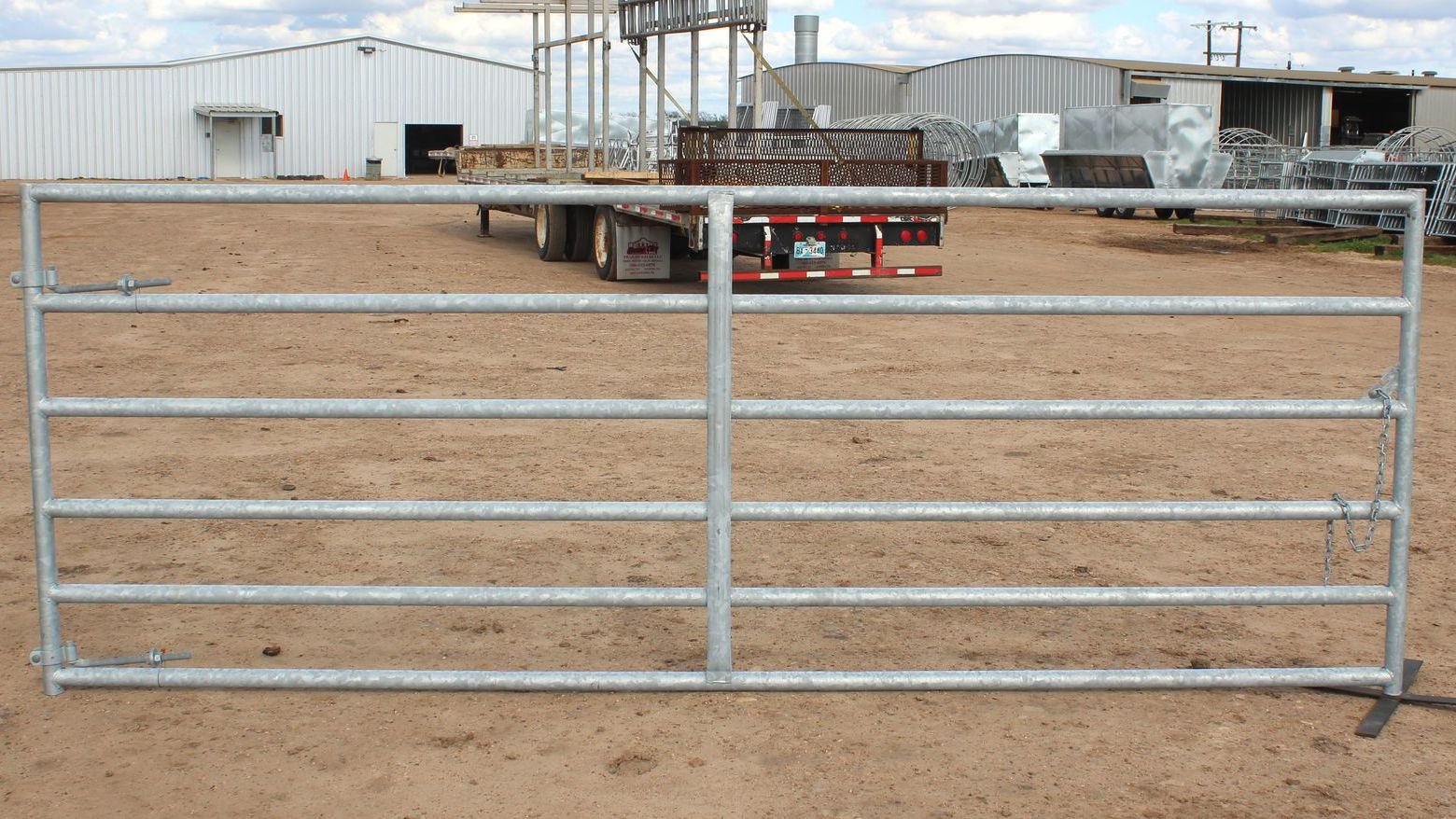 A truck is parked behind a metal fence in a dirt field.