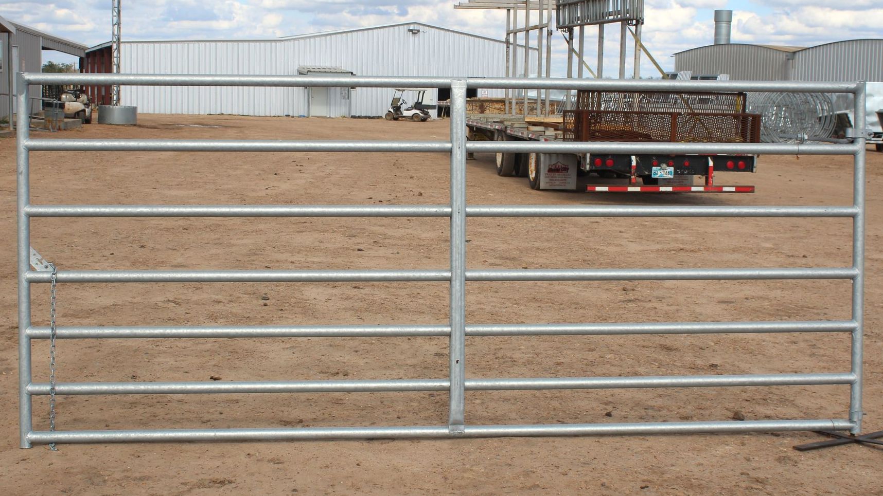 A truck is parked behind a metal gate in a dirt field