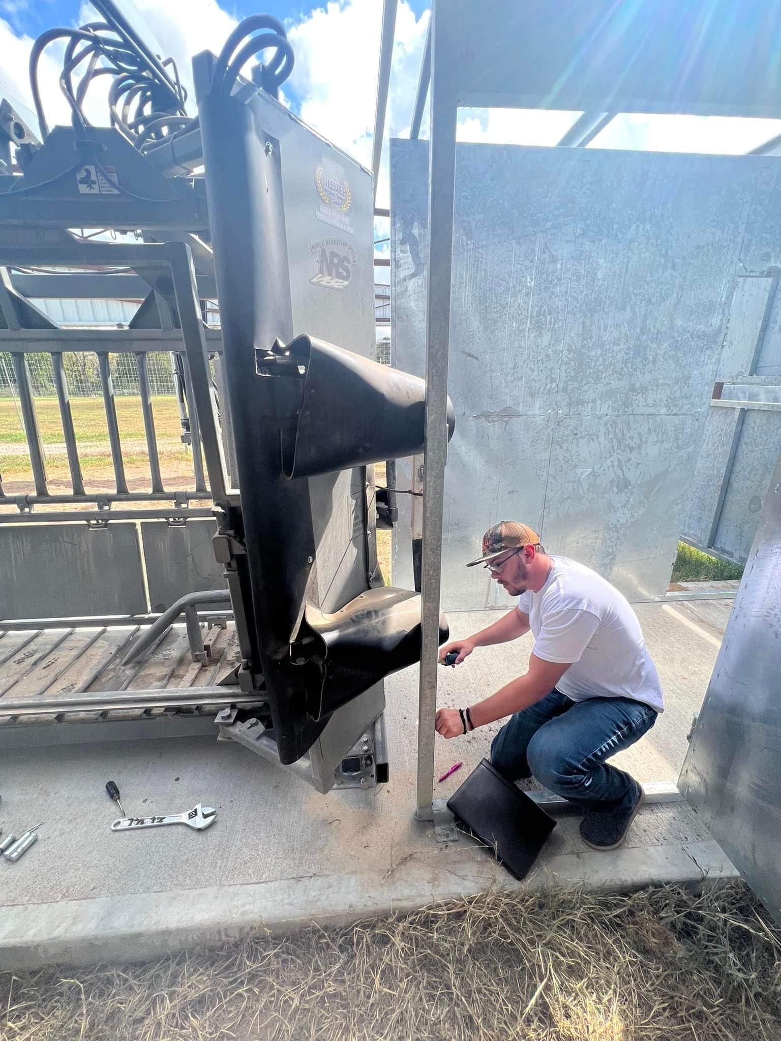 A man is measuring a deer working chute with a tape measure.