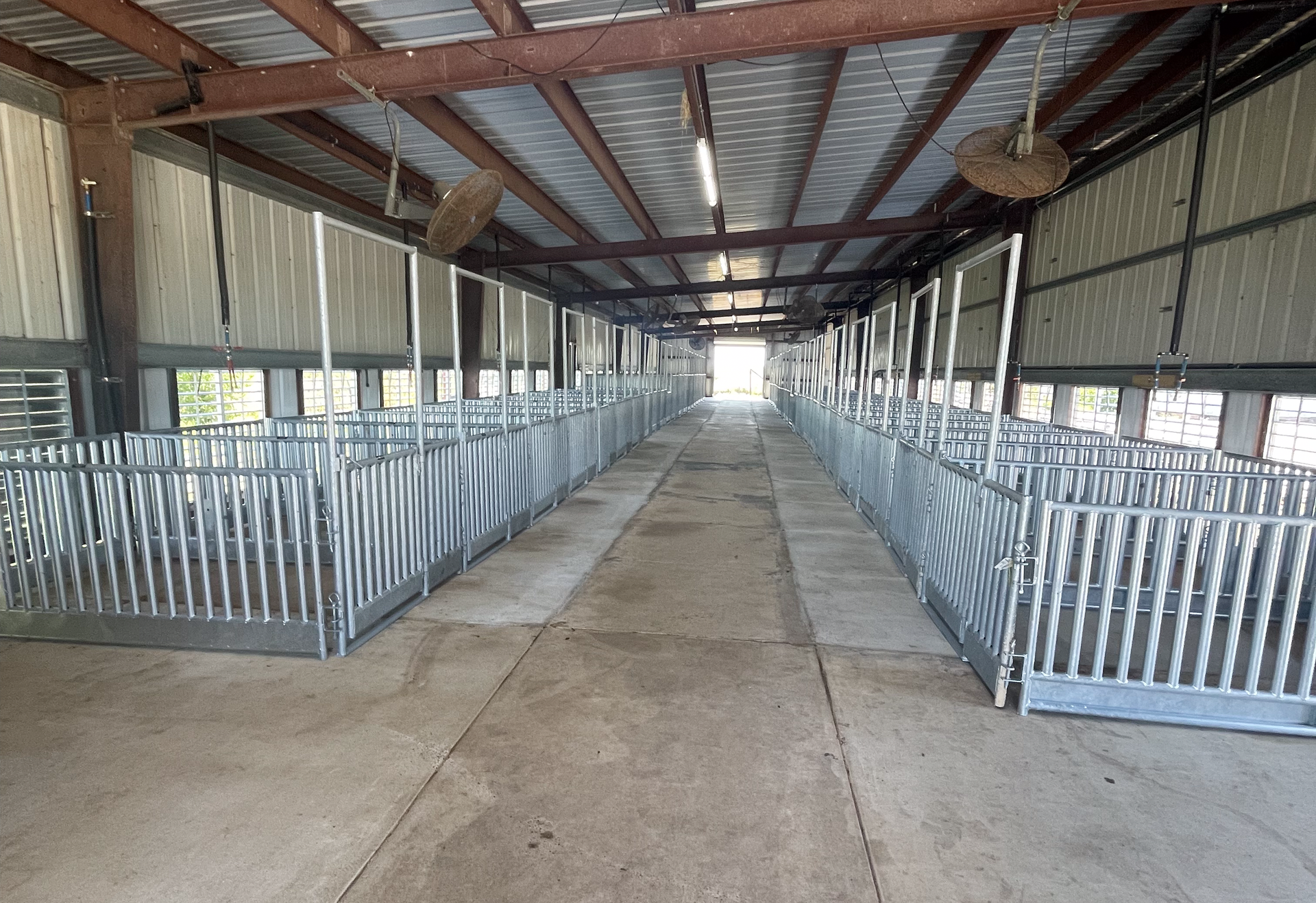 A large empty barn with a lot of fences and a ceiling fan.