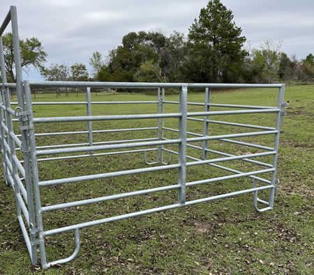 A galvanized gate is sitting in the middle of a grassy field.