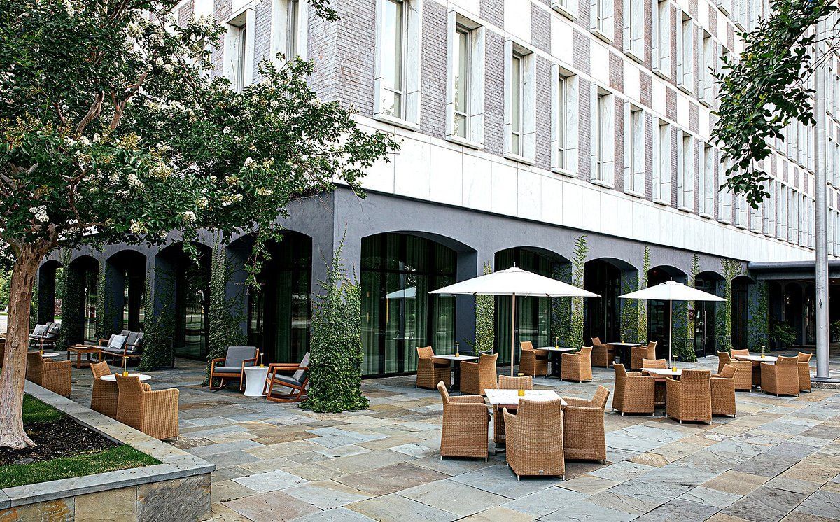 A large building with tables and chairs and umbrellas in front of it