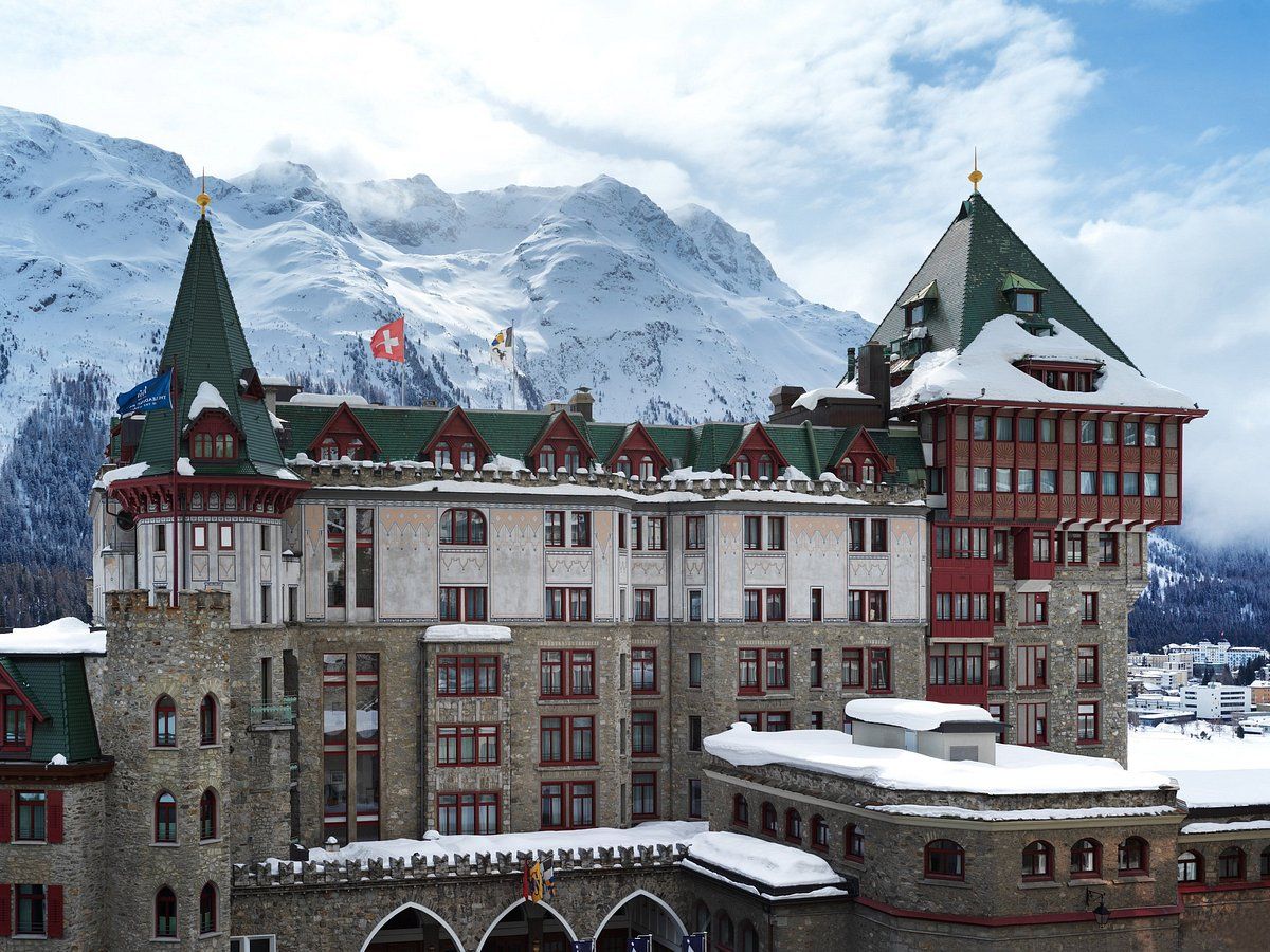 A large building covered in snow with mountains in the background