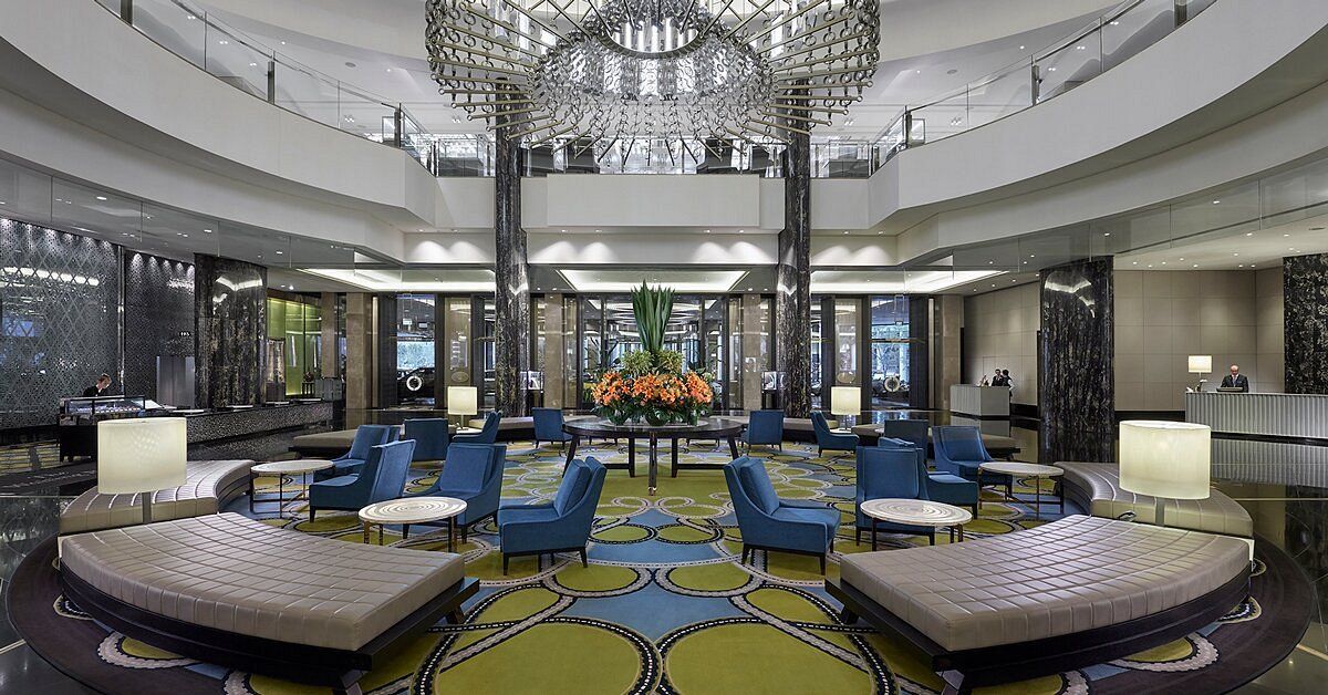 A large lobby of a hotel with a chandelier hanging from the ceiling.