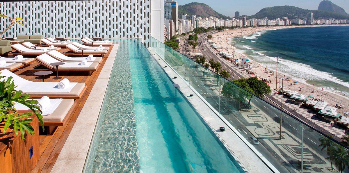 There is a swimming pool on the roof of a building overlooking the ocean.