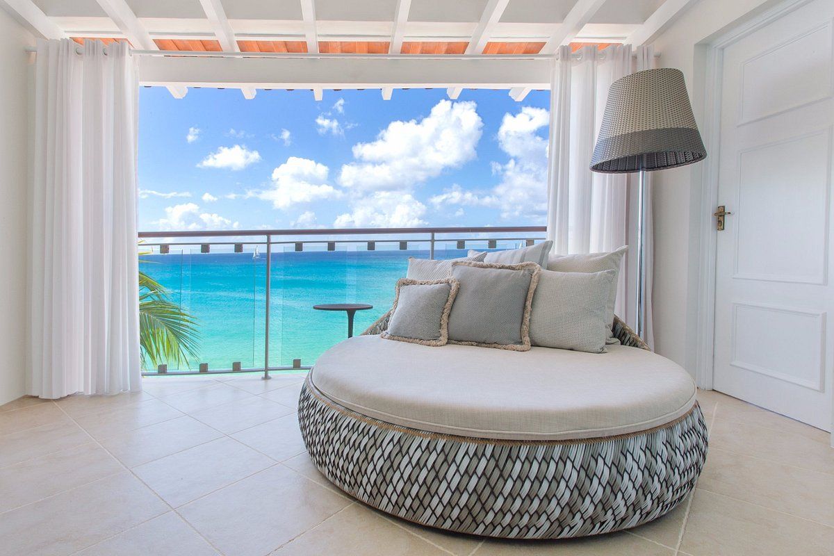 A round bed is sitting in front of a balcony overlooking the ocean.