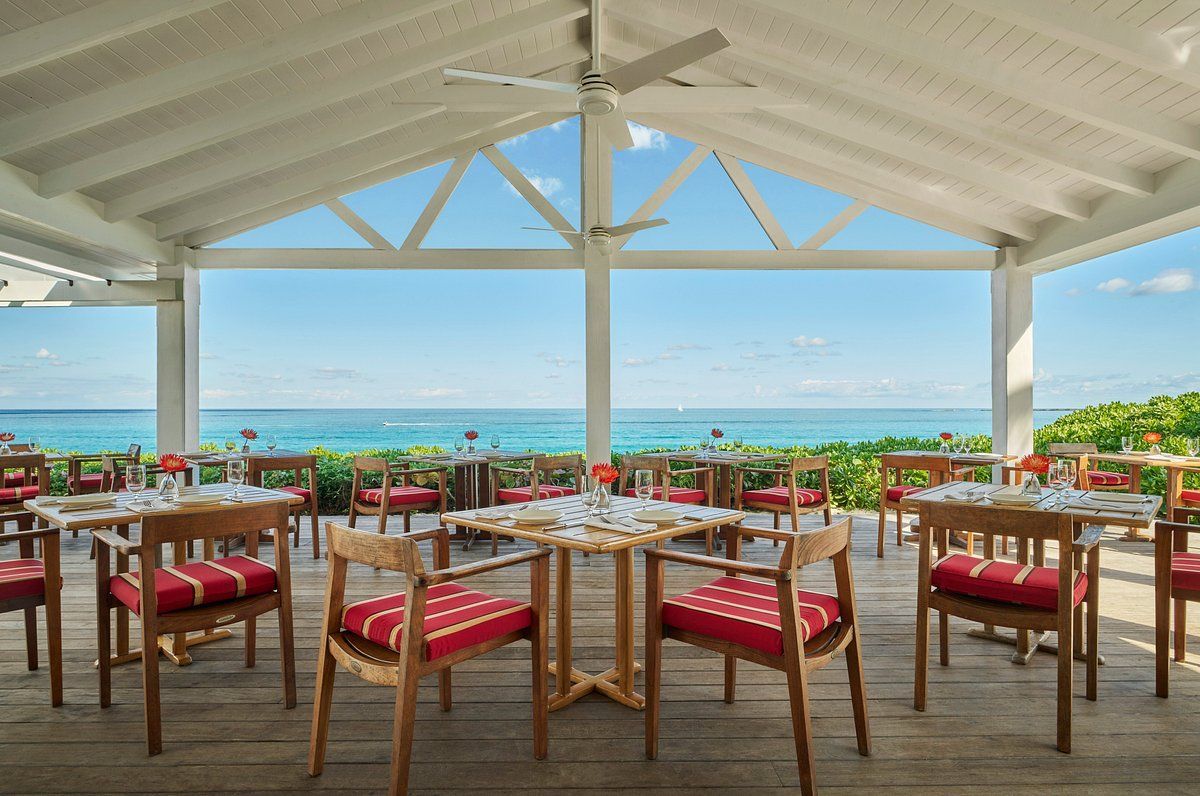A restaurant with tables and chairs overlooking the ocean.