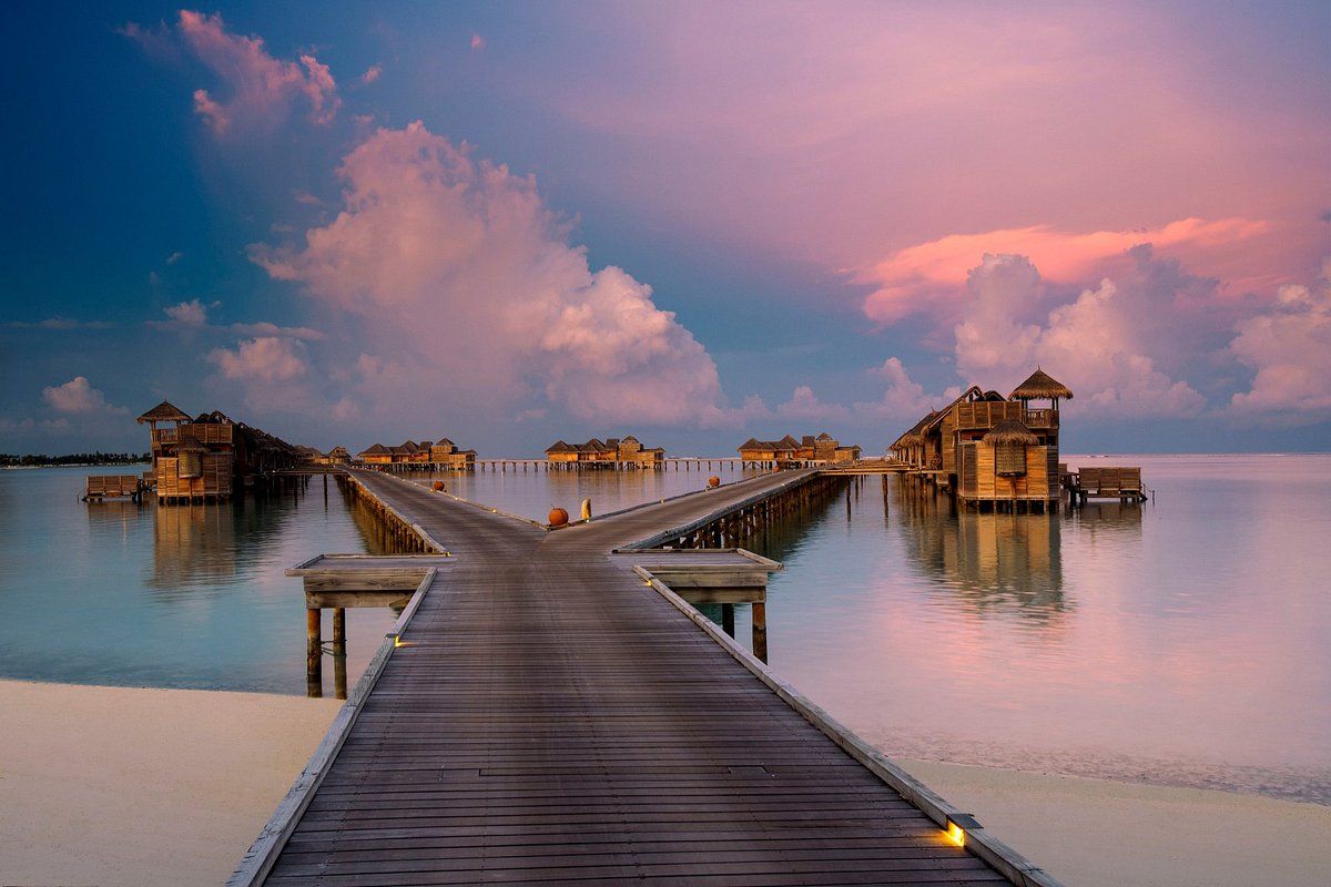 A wooden pier leading to a small island in the middle of the ocean.