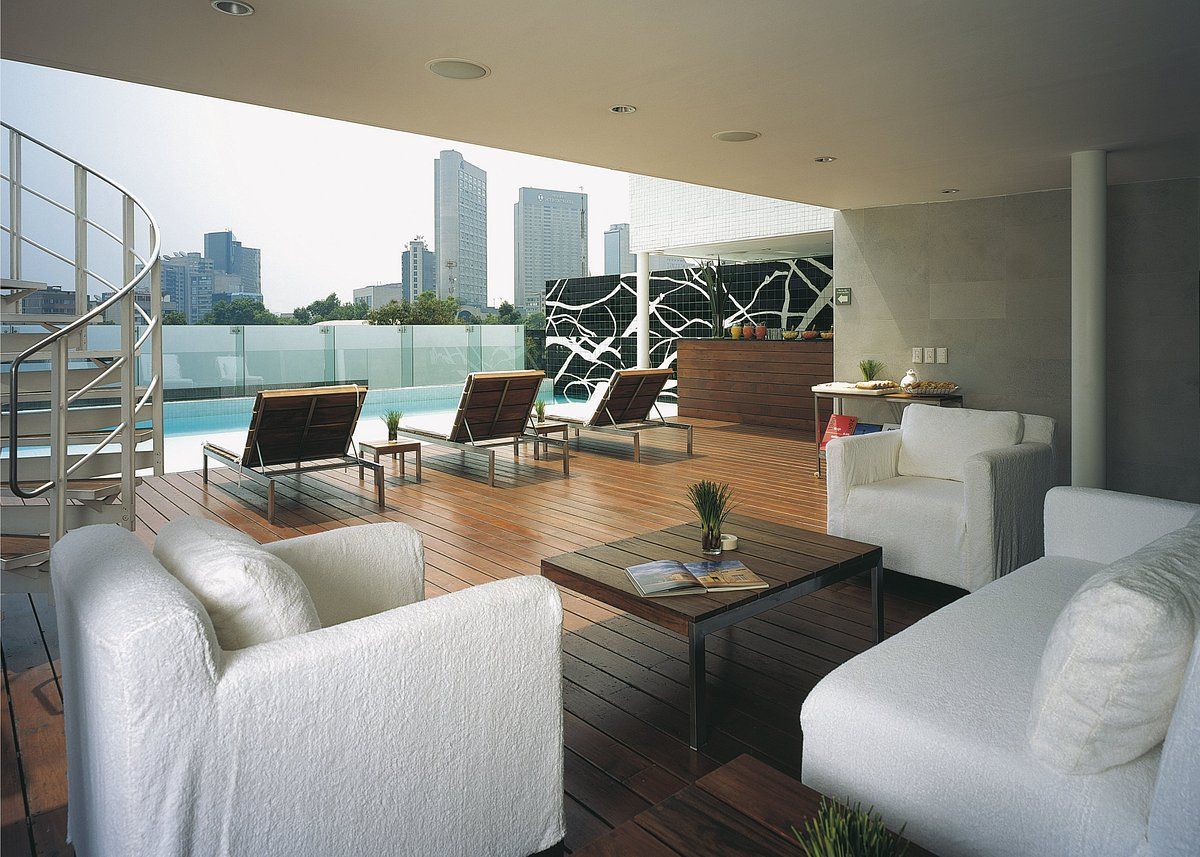 A living room with white furniture and a swimming pool in the background