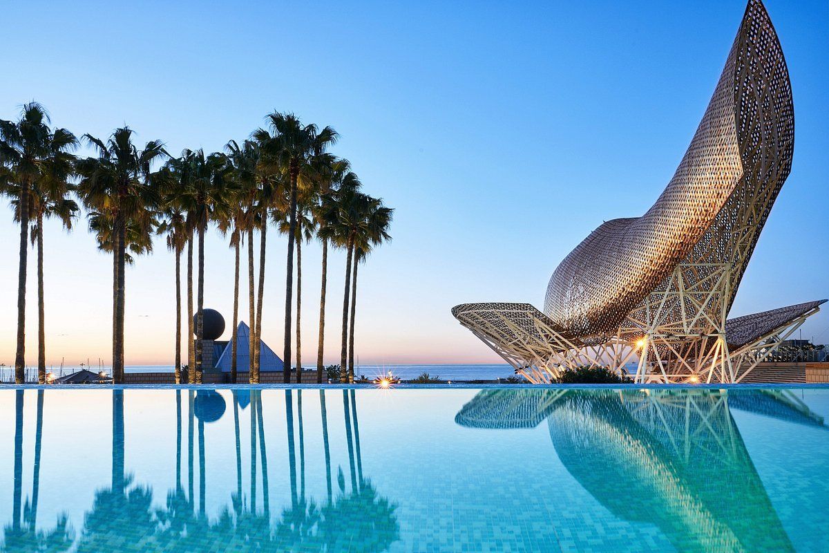 A swimming pool with palm trees and a sculpture in the background
