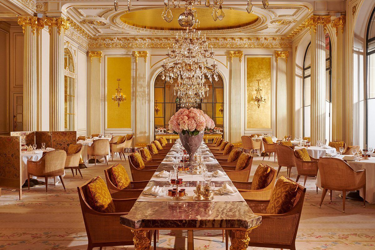 A large dining room with a long table and chairs and a chandelier.