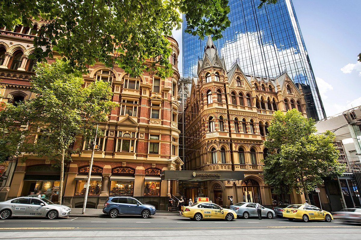 A row of cars are parked in front of a building in a city.