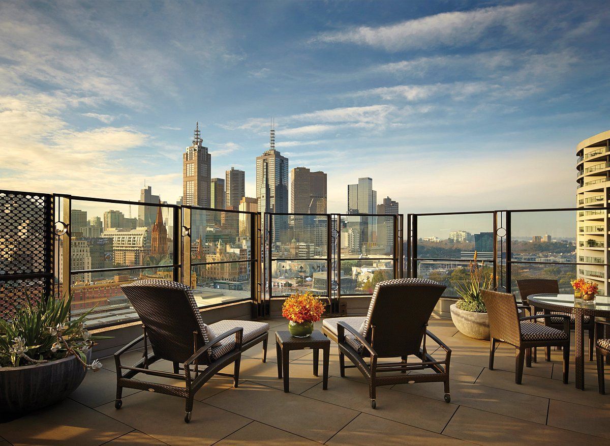 A patio with chairs and a table with a view of the city