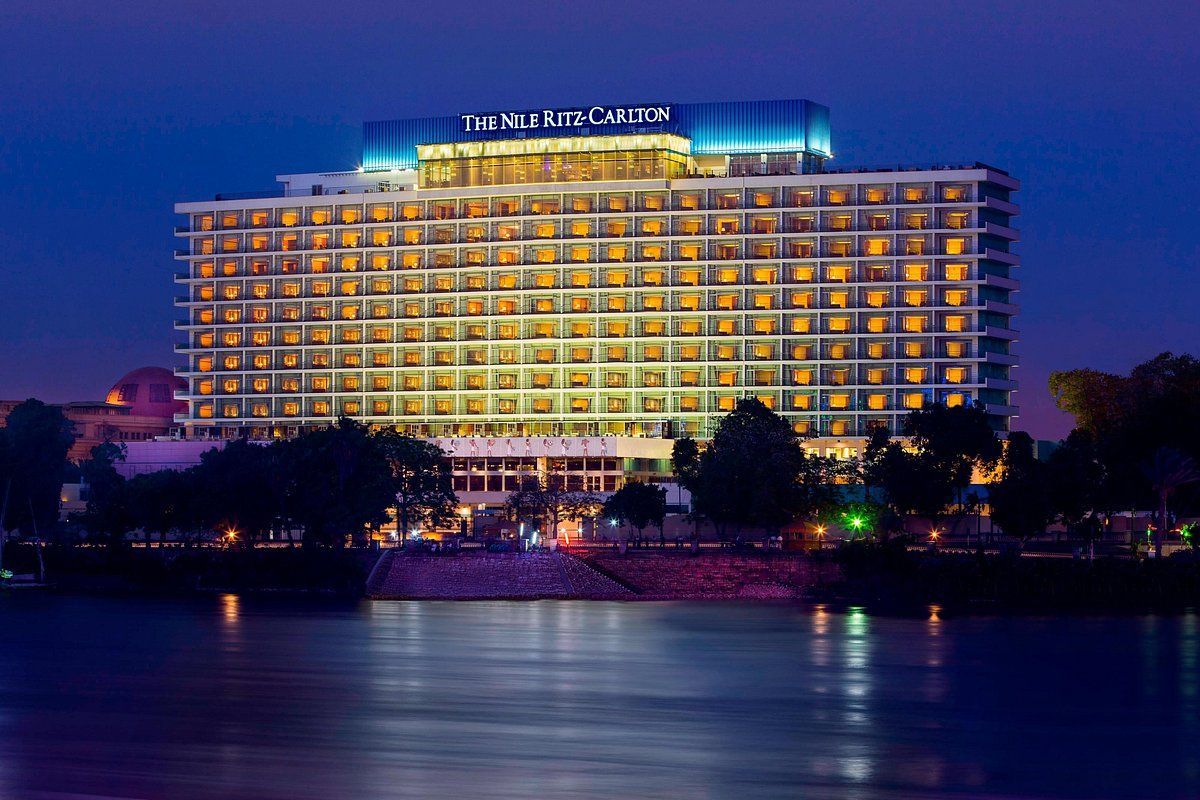 A large building is lit up at night next to a body of water.
