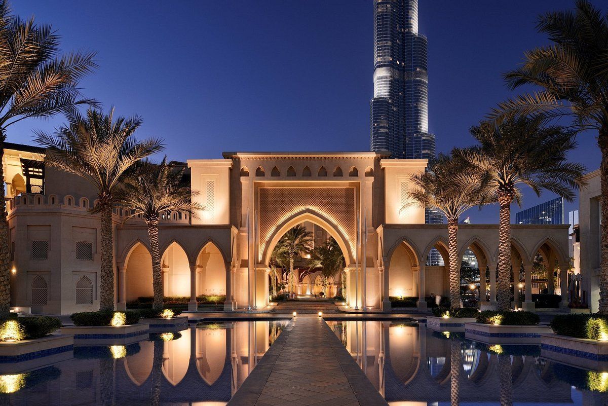 A building with a pool and palm trees in front of it