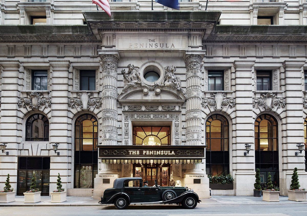 A black car is parked in front of a large building