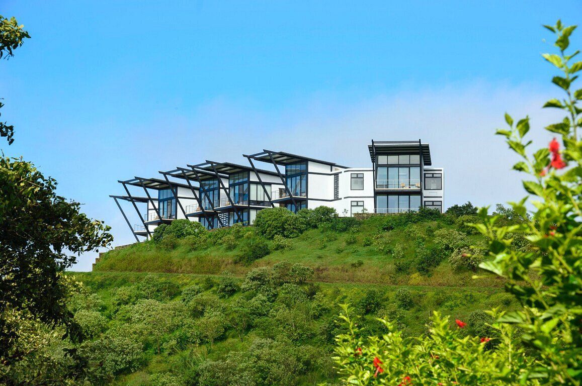 A large house is sitting on top of a hill surrounded by trees.