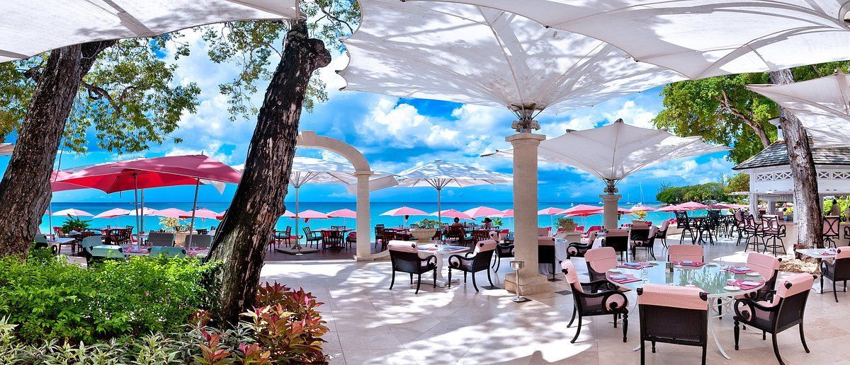 A restaurant on the beach with tables and chairs and umbrellas.