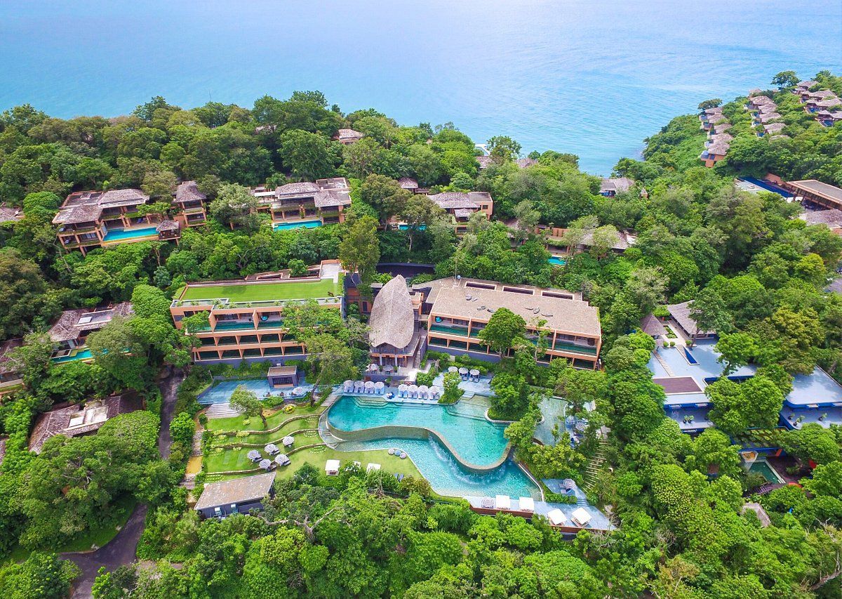 An aerial view of a resort surrounded by trees and buildings next to the ocean.