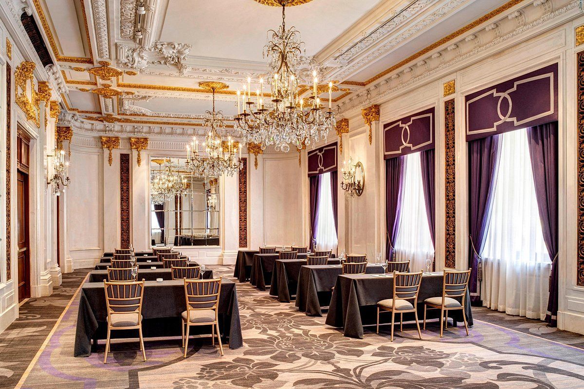 A large room with tables and chairs and a chandelier.