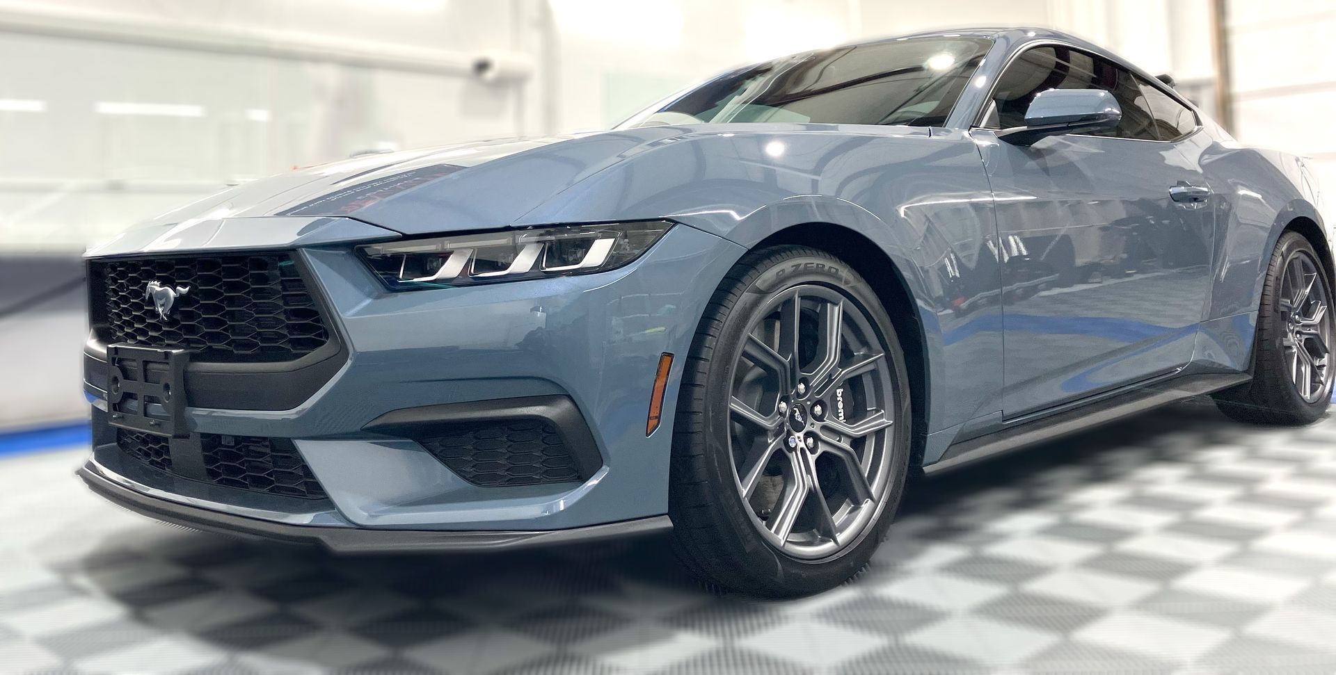 A blue ford mustang is parked in a garage.
