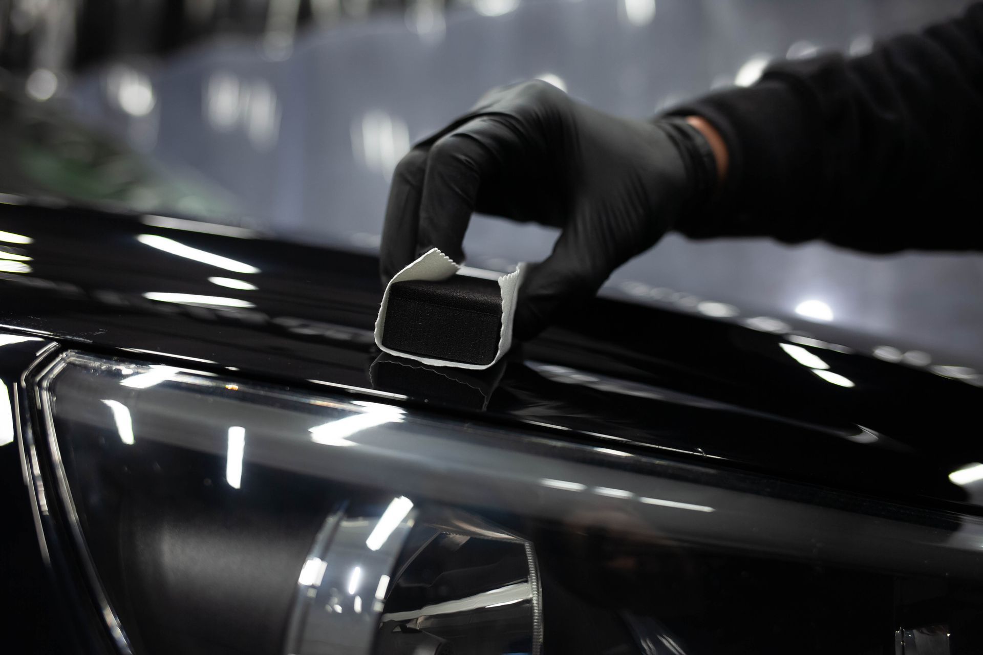 A person is polishing the hood of a car with a sponge.
