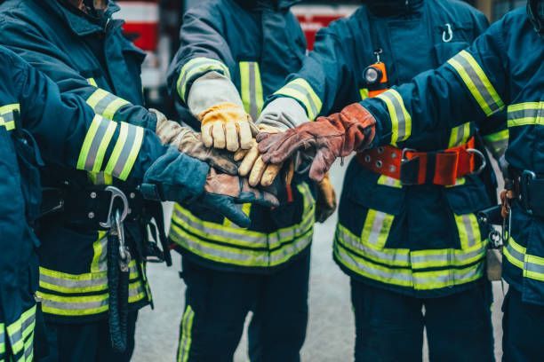 A group of firefighters are putting their hands together.