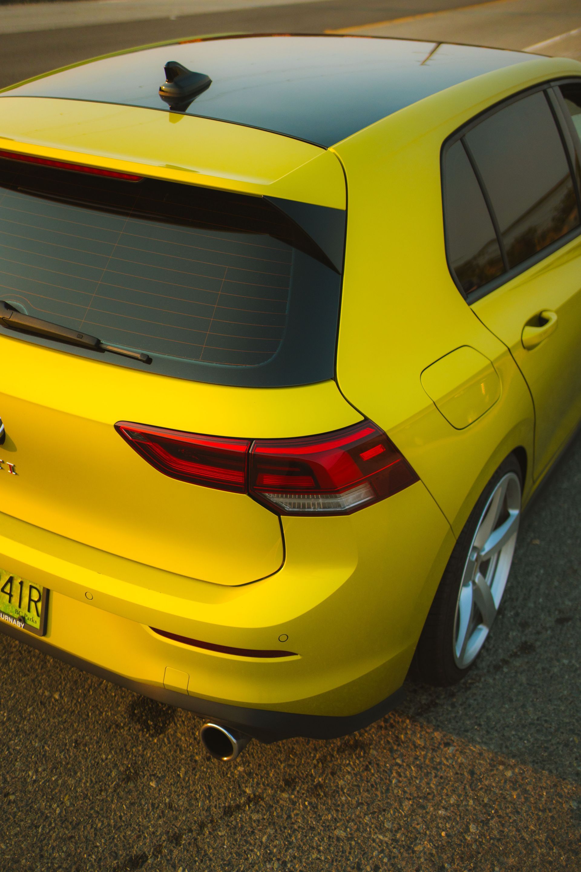 A yellow sports car is parked in front of a wooden building.