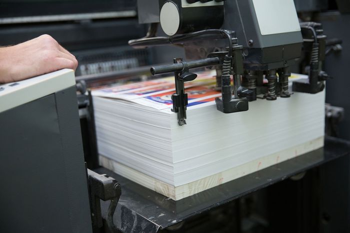 A person is working on a printing machine in a printing factory.