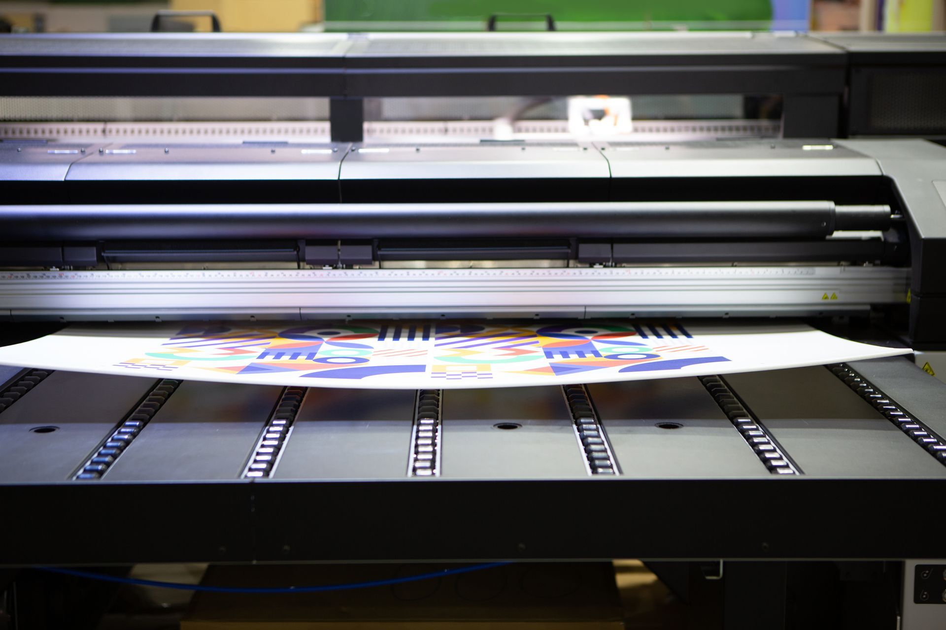 A large printer is printing a piece of paper on a table.