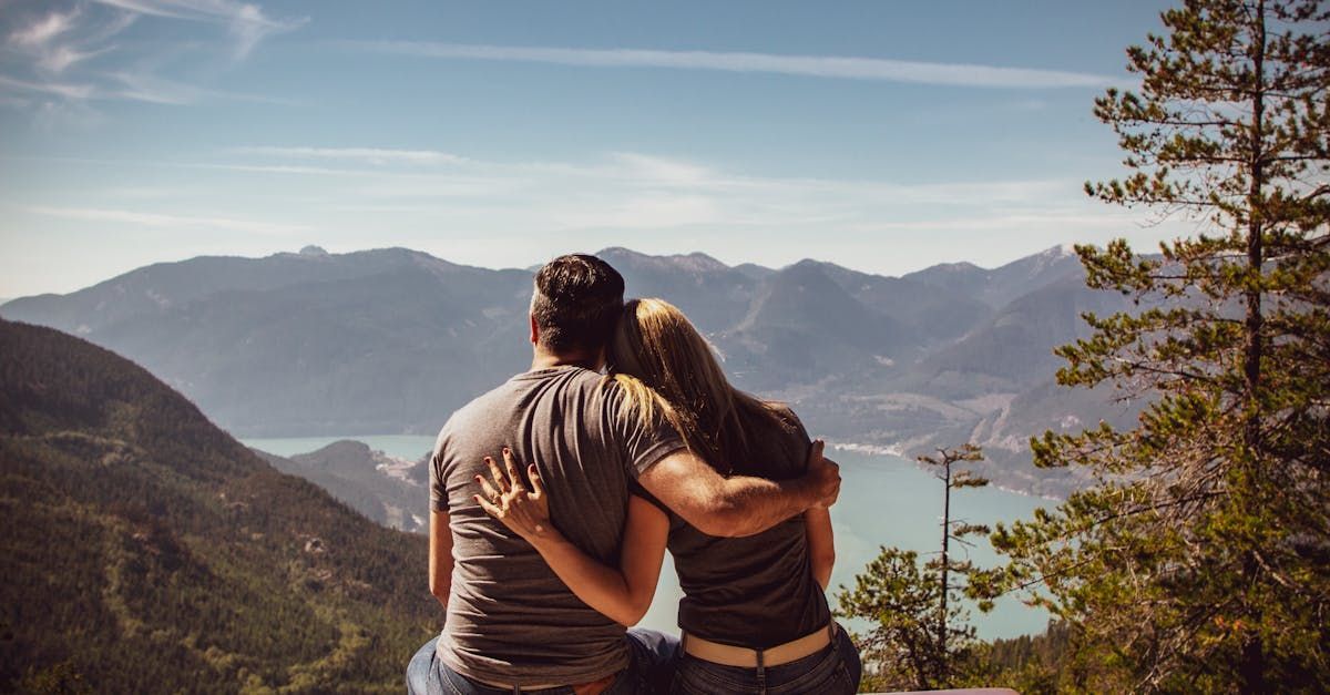 A man and a woman are sitting on top of a mountain looking at the mountains.