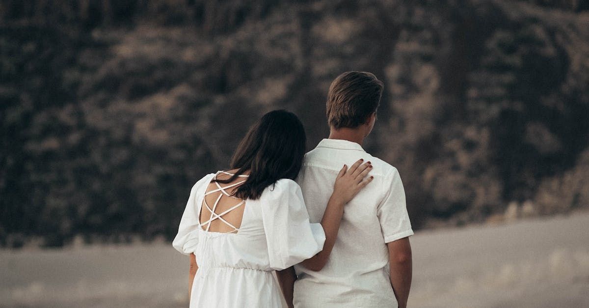 A man and a woman are standing next to each other on a beach.