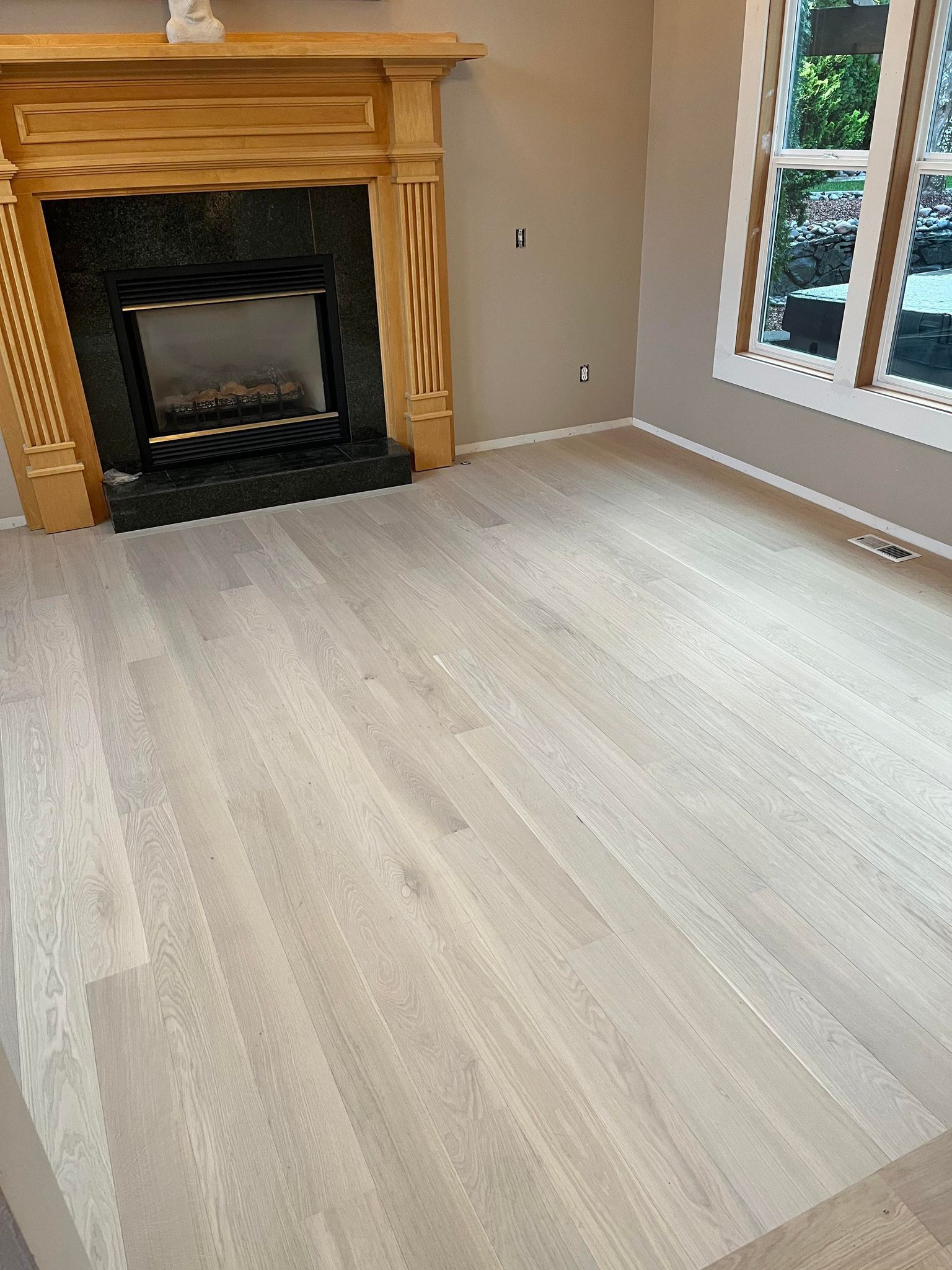 A wooden floor in a hallway leading to a living room.