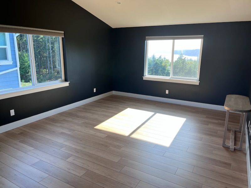 An empty living room with hardwood floors and lots of windows