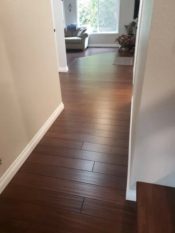 A hallway with hardwood floors leading to a living room.