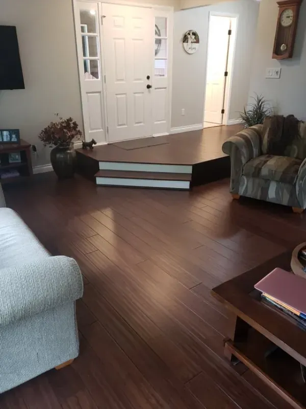 A living room with hardwood floors , a couch , a chair and a table.