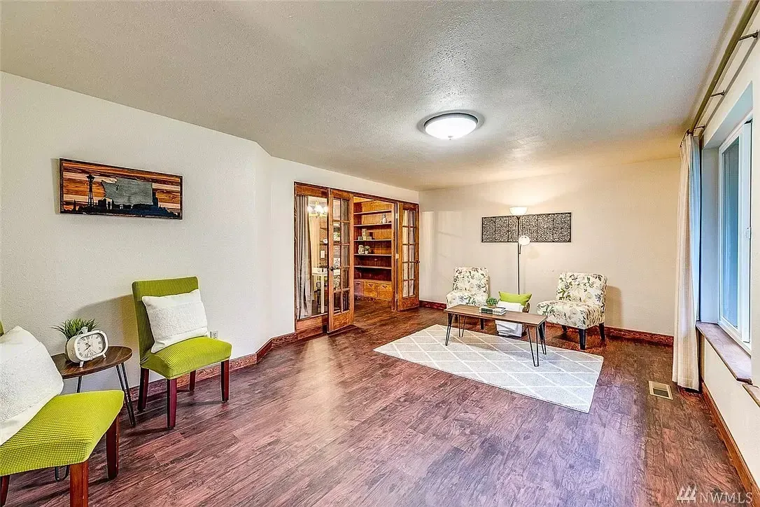 A living room with hardwood floors , green chairs and a coffee table.