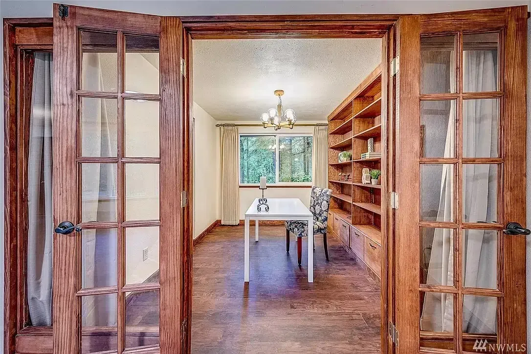A room with a table and chairs in it and french doors leading to it.