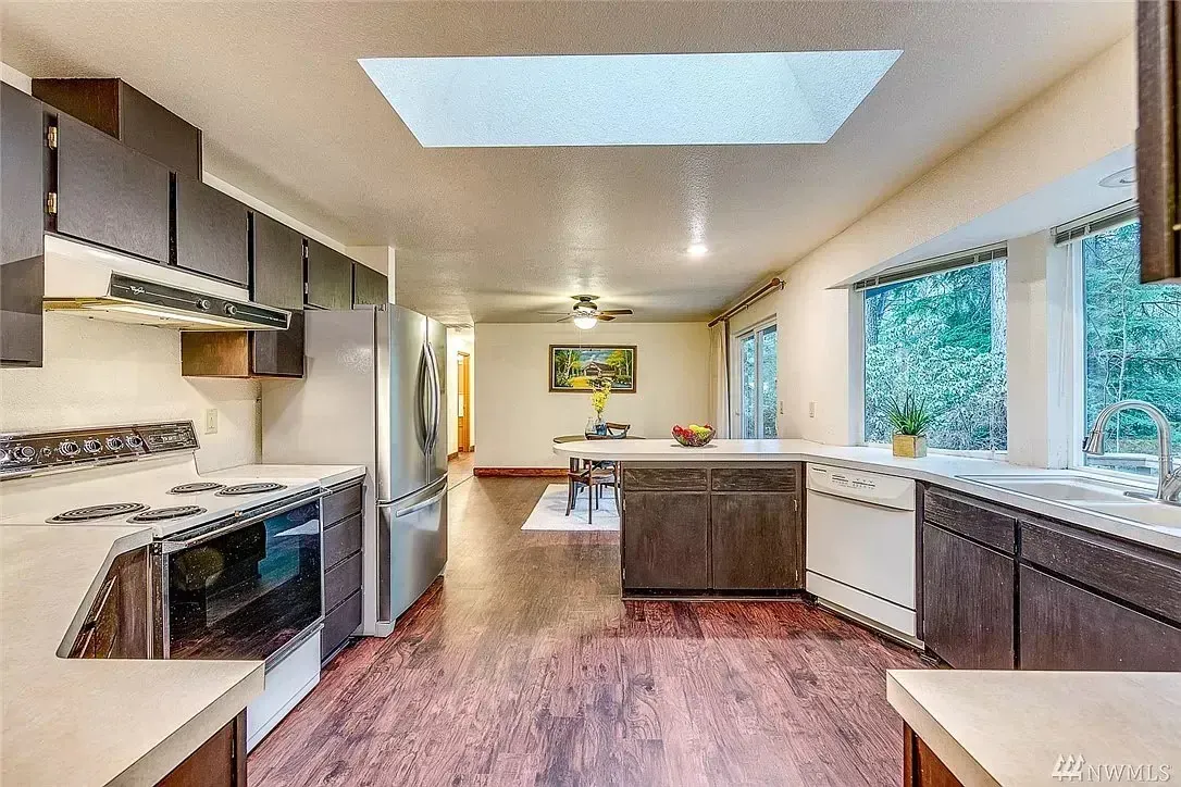 A kitchen with a skylight above the stove and a living room.
