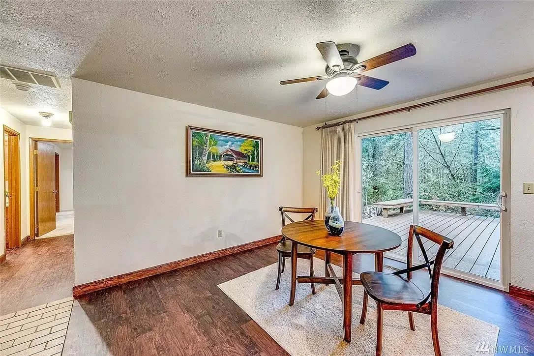 A dining room with a table and chairs and a ceiling fan.