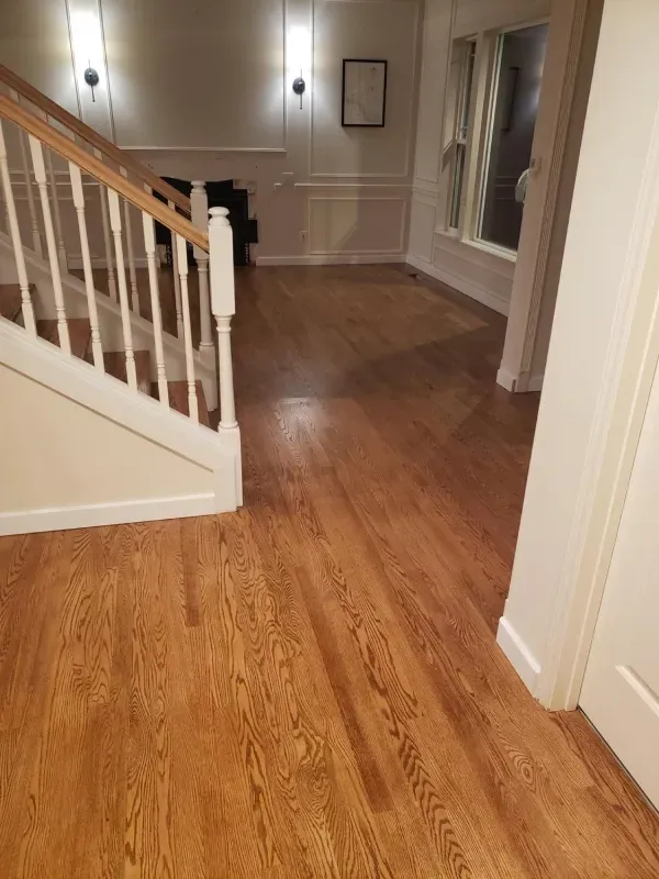 A hallway with hardwood floors and stairs in a house.