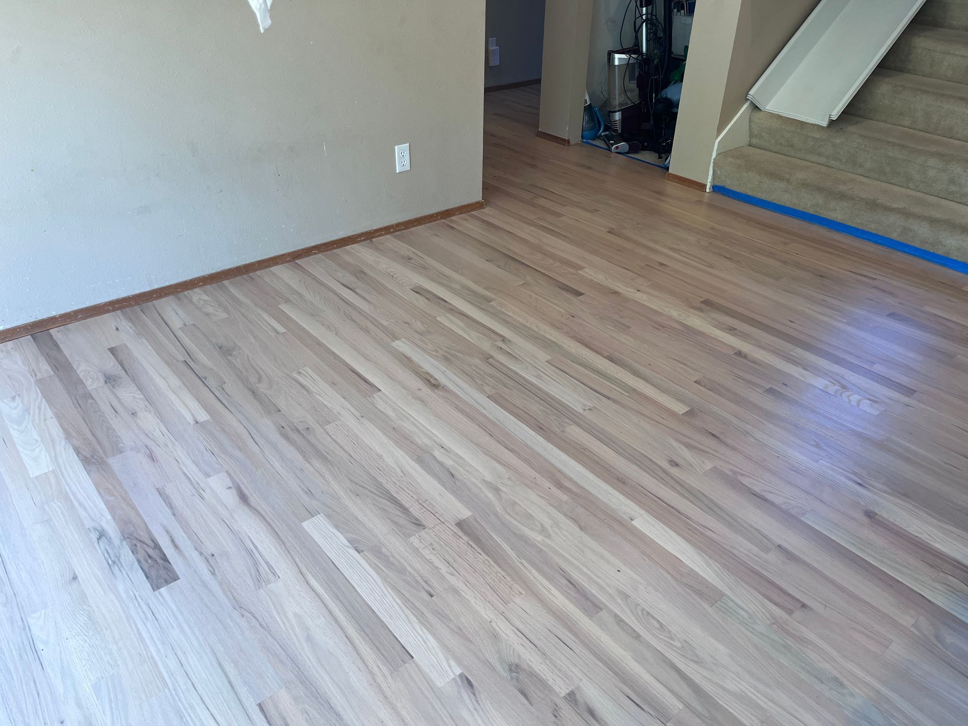 A room with a wooden floor and stairs in the background