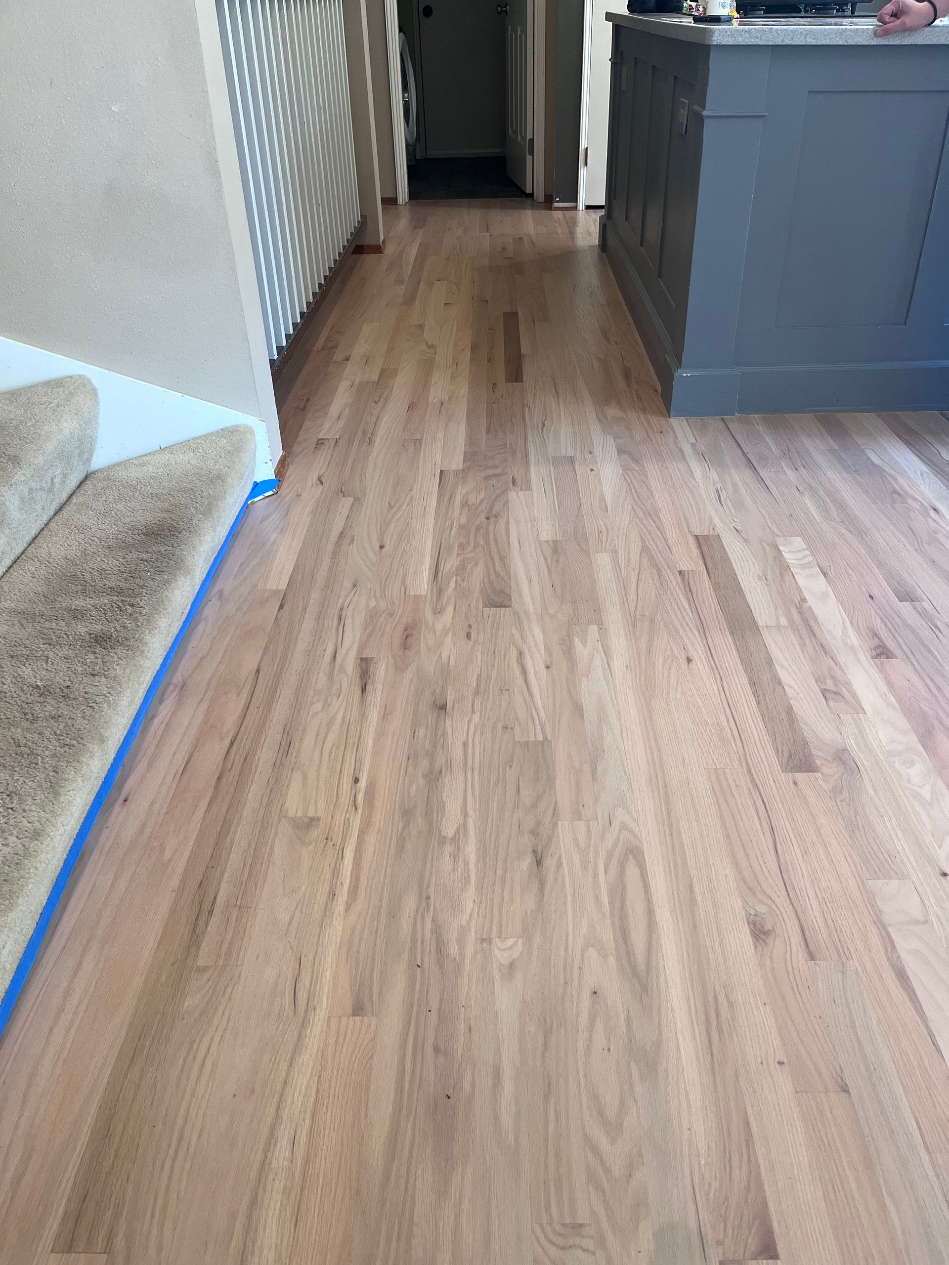 A wooden floor in a room with stairs and a counter.